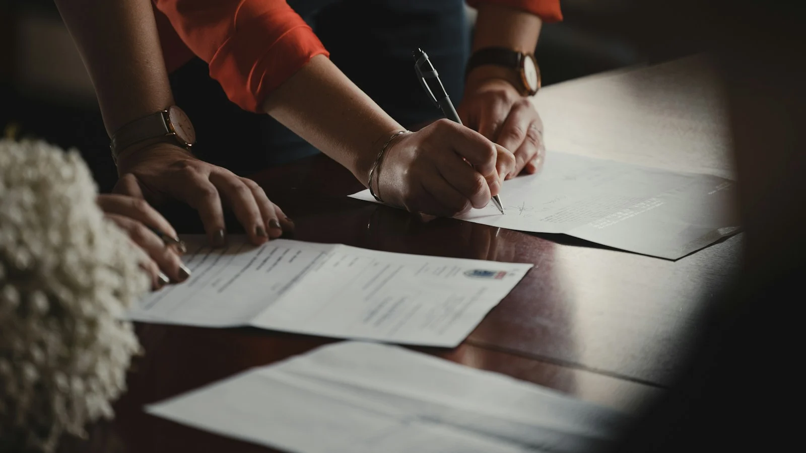 Pessoas assinando documentos sobre uma mesa